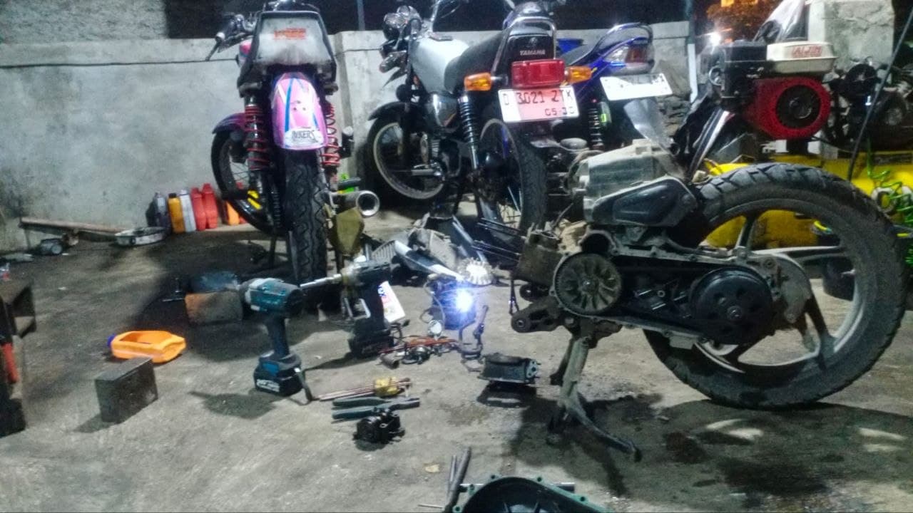 Motor yang sedang dikerjakan di lantai bengkel